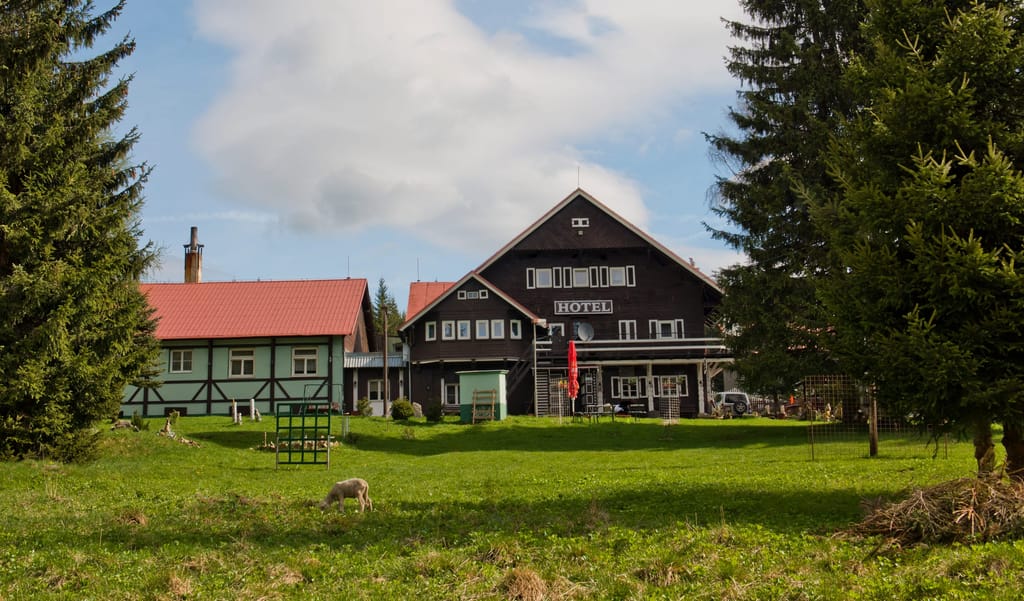 Hauptgebäude des Hotels mit rotem Dach und grüner Wiese im Sommer