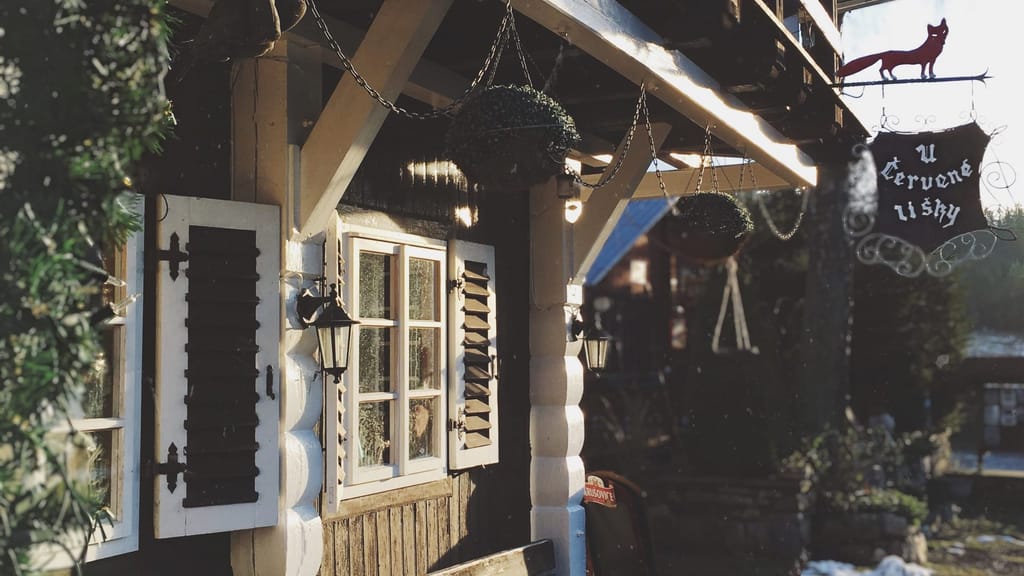 Vchod do restaurace U Červené lišky s dřevěnými okenicemi a vývěsním štítem