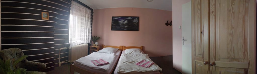Dvoulůžkový pokoj s oddělenými postelemi, tmavým obkladem stěn a dřevěnou skříní
