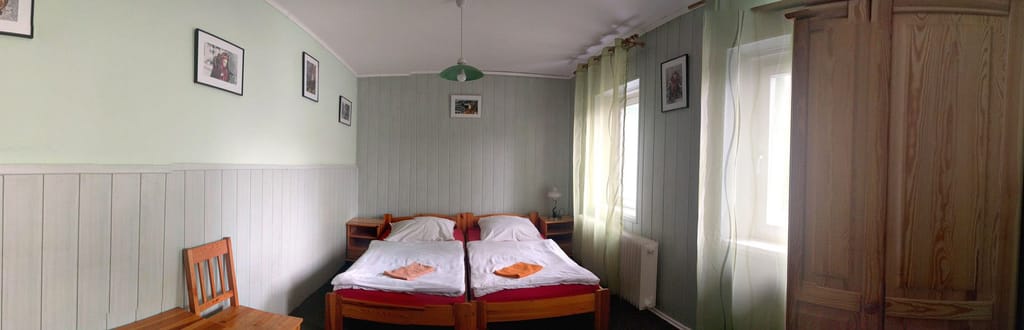 Světlý dvoulůžkový pokoj se zeleným obkladem a obrázky na stěně