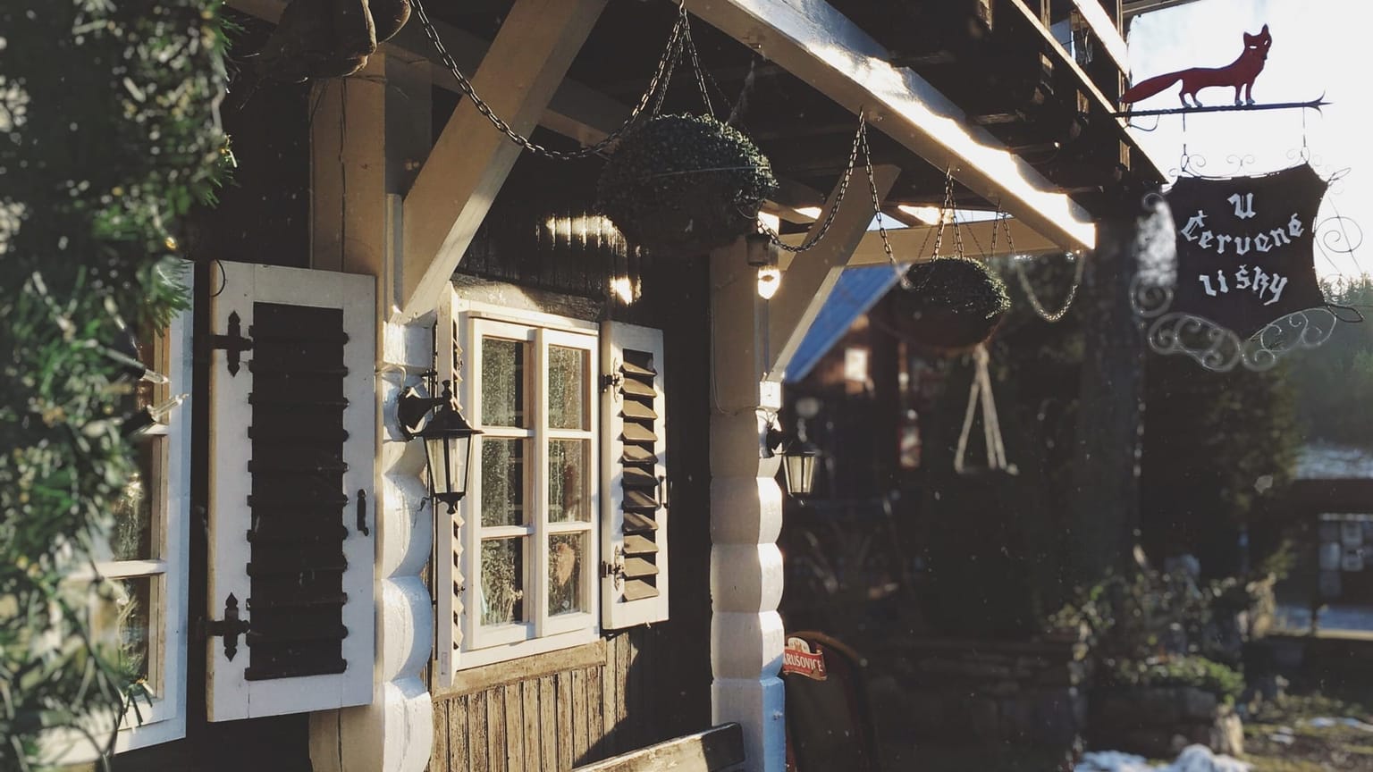 Vchod do restaurace U Červené lišky s dřevěnými okenicemi a vývěsním štítem